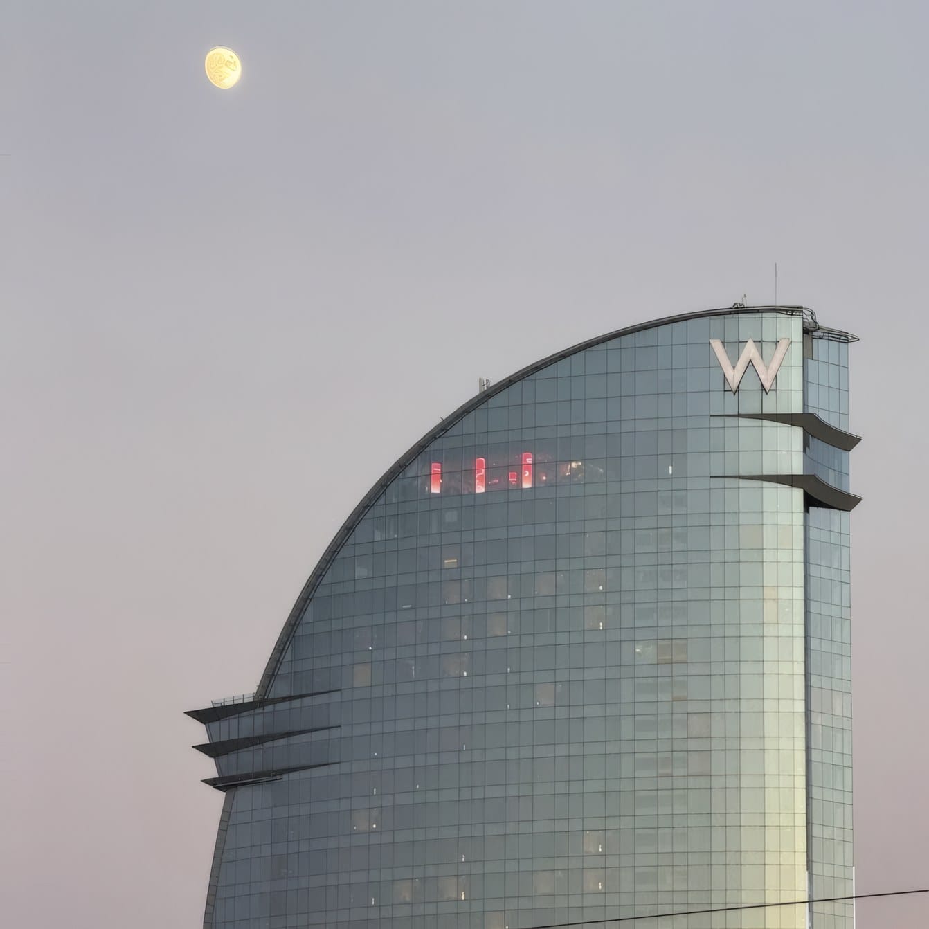 The W Hotel on Barcelona's seafront at dusk, with the moon above