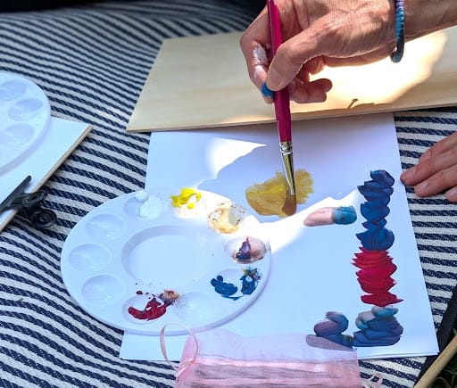 A hand holding a brush next to a watercolour palette during a botanical drawing class
