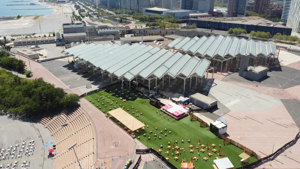Aerial view of Parc del Fòrum in Barcelona, with its large canopies, a lawn and the seafront, outside festival week