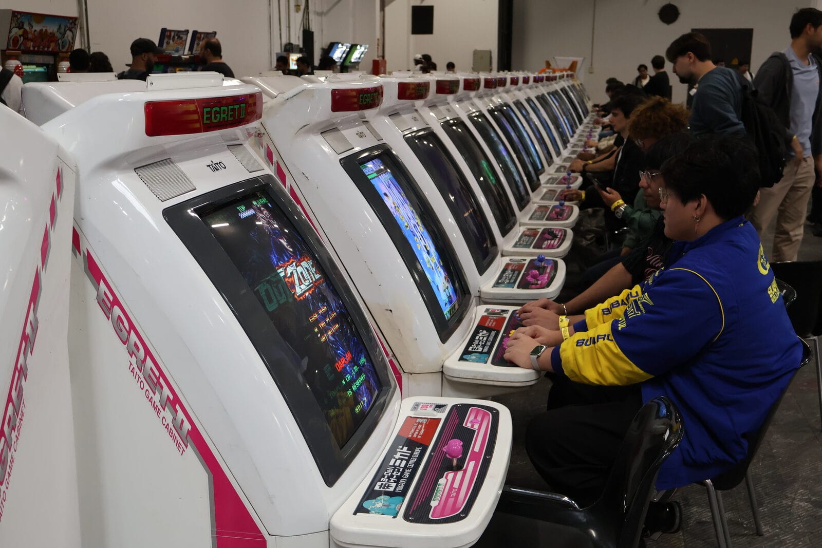 Row of Japanese arcade cabinets with players at the screens