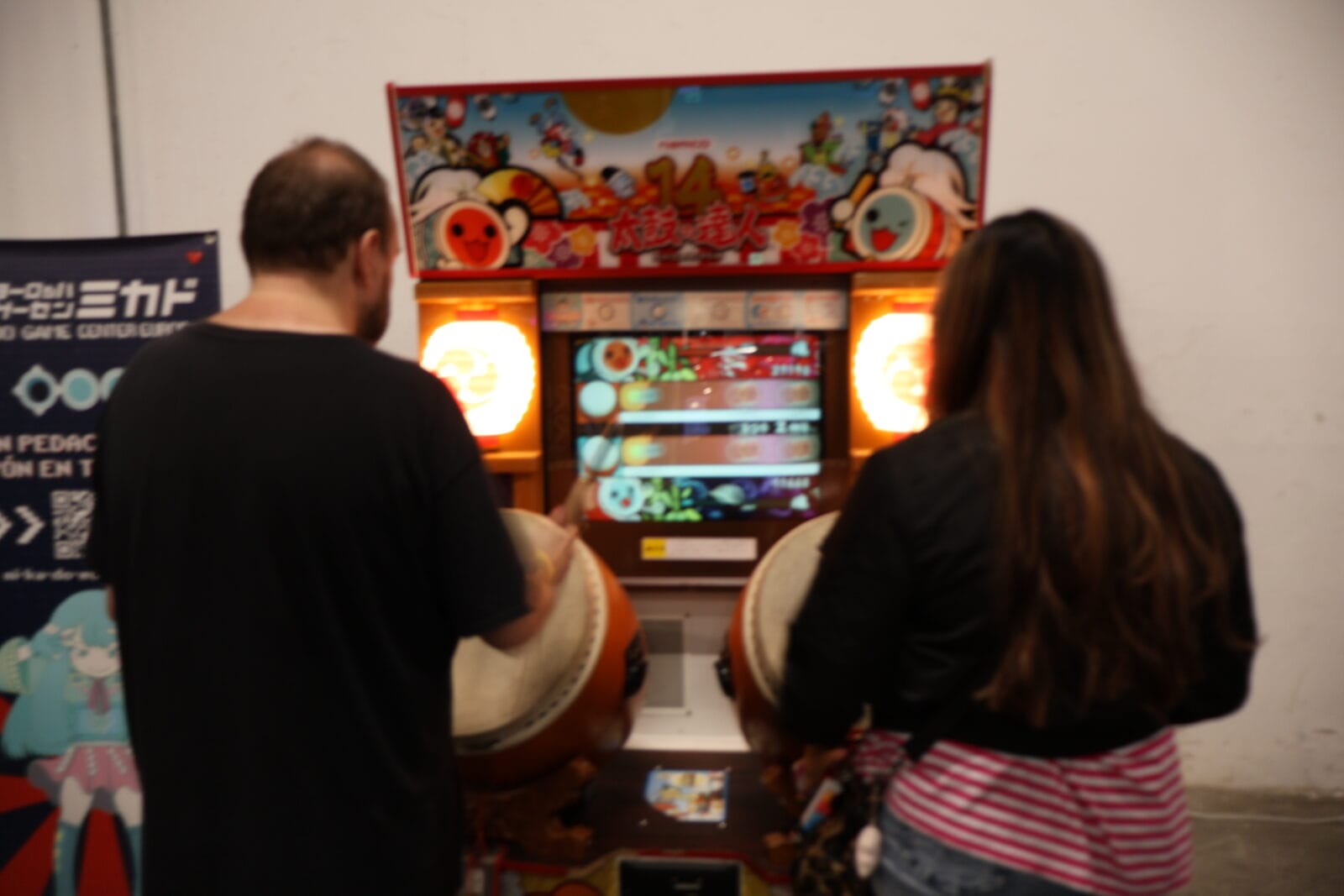 Two visitors try their hand at a Japanese drumming arcade game