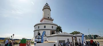Llobregat Lighthouse at the Port of Barcelona, a cylindrical building with a quadrangular tower and glass dome, with ships in