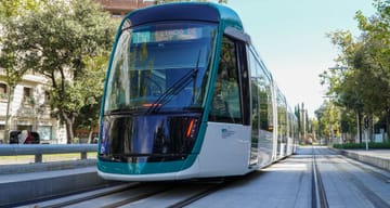 Trambesòs tram travelling along a street in Barcelona with buildings in the background