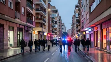 Police patrol car driving through a street in L'Hospitalet de Llobregat, with residential buildings in the background.