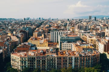 Police officers in uniform standing on Las Ramblas in Barcelona, with trees and buildings in the background.