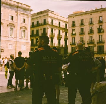 Mossos d'Esquadra officers patrol a busy public area in Catalonia during the summer safety operation.