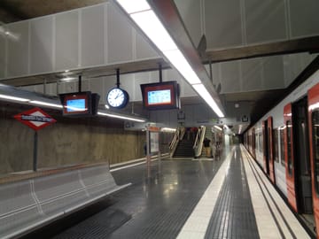 Night-time view of an FGC S2 train arriving at Sabadell Parc del Nord station during a public festival, with illuminated platforms and passengers boarding.