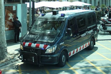 Police officers from the Mossos d'Esquadra standing beside an impounded vehicle with Polish licence plates at Terminal 1 of Barcelona-El Prat Airport.