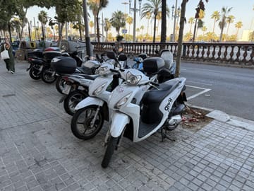 A wheel of an electric moped parked on a street in Barcelona, showing a clean urban mobility option.