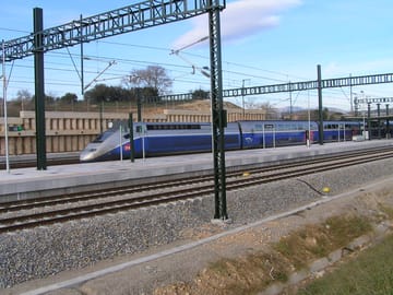 High-speed railway tracks and overhead catenary equipment at a station on the Barcelona to Figueres route in Girona province.