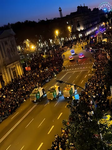 Crowd gathers along the parade route at the 2026 Three Kings Parade in Barcelona, with floats and performers visible under evening lights.