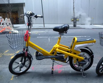 An electric bicycle parked on a pavement in Barcelona, with typical Mediterranean-style buildings in the background.