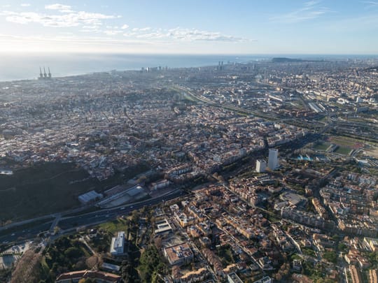 Aerial view of residential blocks and transport infrastructure in Barcelona's metropolitan area.