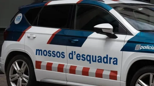 Police tape and a Mossos d'Esquadra patrol car at a crime scene in a residential area of Lleida