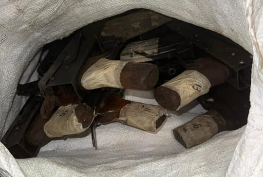 A dozen AK-74 assault rifles displayed on the ground after being seized by police.