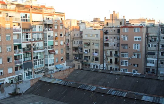 Workers in protective suits remove asbestos panels from the roof of a large industrial building in Barcelona.