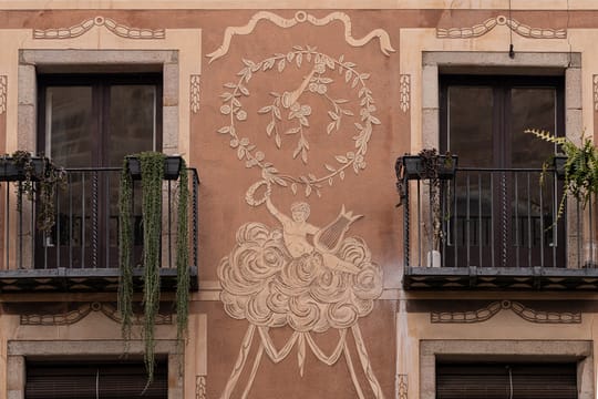 A detailed view of a Baroque sgraffito façade in Barcelona, showing intricate decorative patterns and figures.