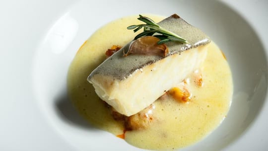 A plate of cod 'a la llauna' with crispy skin and beans, served in a traditional Barcelona restaurant.