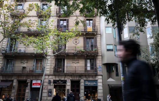 A view of multiple residential buildings in Barcelona's Eixample district under a clear sky, showing dense urban housing.