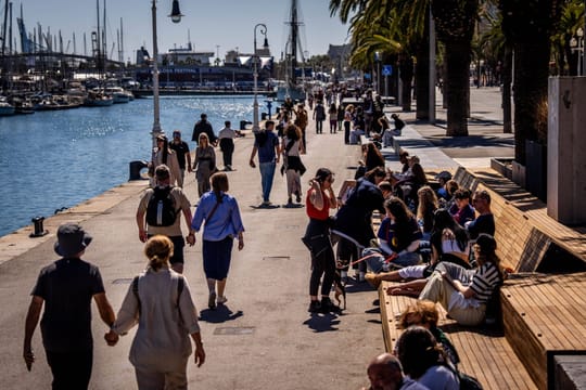 People enjoying a sunny day on a Barcelona beach with clear skies and warm temperatures.
