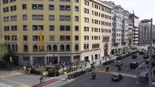 A wide, tree-lined street in Barcelona with expanded pavements and reduced car traffic, showing pedestrians and cyclists enjo