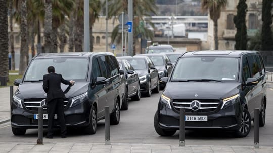 A high-end Mercedes-Benz VTC vehicle parked on a Barcelona street, with a blurred city background.