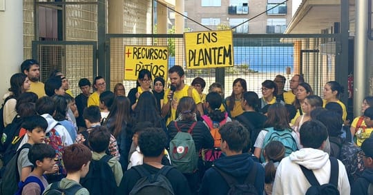 Teachers and education professionals holding protest signs and blocking a street in Catalonia during an education sector demo