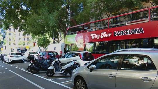 Tourist buses stuck in traffic on a narrow street near Sagrada Familia in Barcelona's Eixample district.