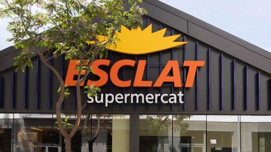 Exterior view of a modern Esclat hypermarket building with large glass windows and a prominent red logo against a clear sky.