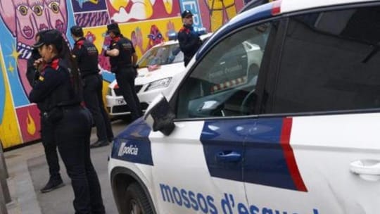 Police car with flashing lights parked outside an apartment building in Barcelona, representing a crime scene.