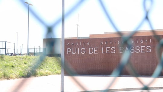 Exterior view of a modern prison facility with high walls and watchtowers under a clear sky, symbolising the Catalan prison s