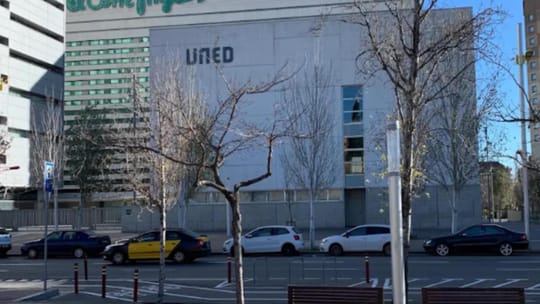 A group of people holding protest signs outside a university building, with some signs mentioning 'UNED' and 'dignidad'.
