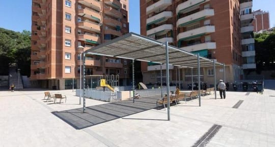 Newly renovated street in Barcelona's Can Baró neighbourhood with wide pavements and new paving, showing improved pedestrian 