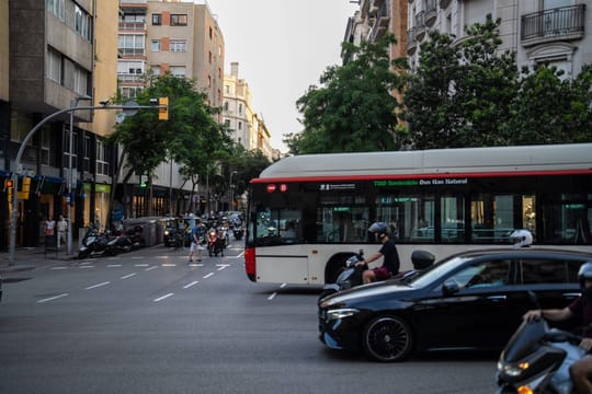 A white car with front-end damage after colliding with a red and white Transports Metropolitans de Barcelona (TMB) bus on a c