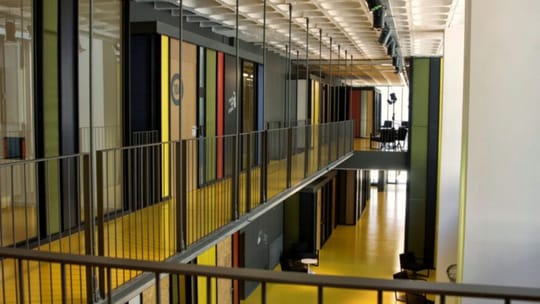 Modern building exterior of a municipal innovation hub with people entering, representing the Barcelona care economy hub.