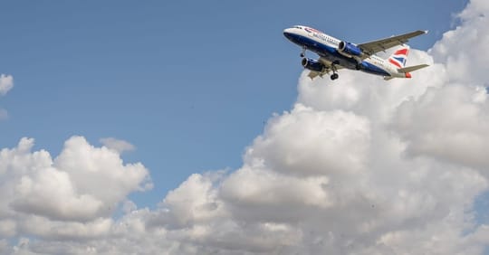 An aeroplane taking off from Barcelona-El Prat Airport with the city skyline in the background.