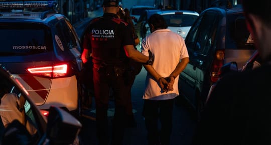 Police car with flashing lights parked on a street in a Barcelona neighbourhood at night.