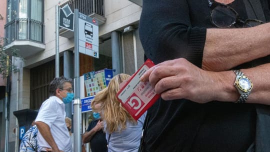 Person tapping a Tarjeta Rosa transport card at a Barcelona Metro turnstile.