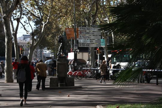 A view of Plaça d'Urquinaona in Barcelona, showing the central fountain and surrounding historic buildings.