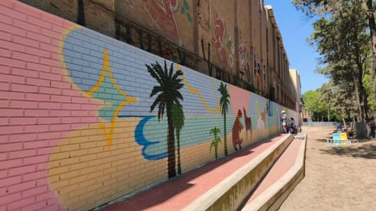 A colourful, abstract participatory mural on a wall in Barceloneta Park, showing various shapes and bright hues.