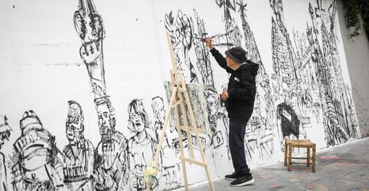 Joan Bueno, a 93-year-old artist, stands proudly next to his newly completed 17-metre mural at BesArt, depicting everyday Bar