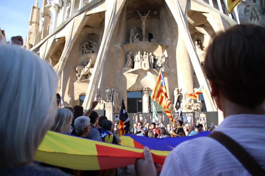 Sagrada Família basilica exterior with people gathered, police presence visible.