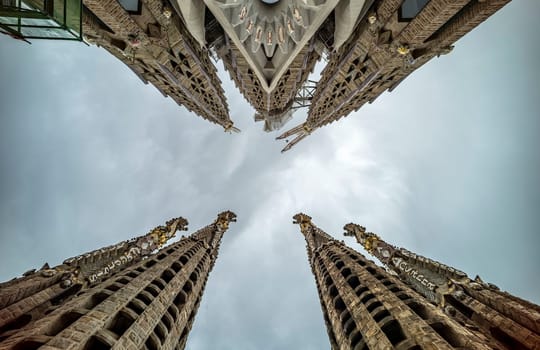 Sagrada Familia's Jesus tower with a large cross, rising above the Barcelona skyline.