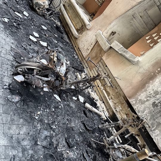 Aerial view of a residential street in Sant Gervasi, Barcelona, showing scorched pavement and damaged waste containers following a series of arson attacks.