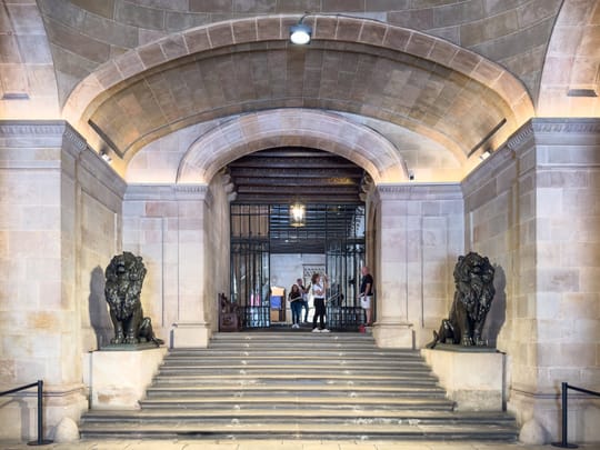 A person using a mobility aid walks near a Generalitat building in Barcelona, symbolising renewed access to disability support services.