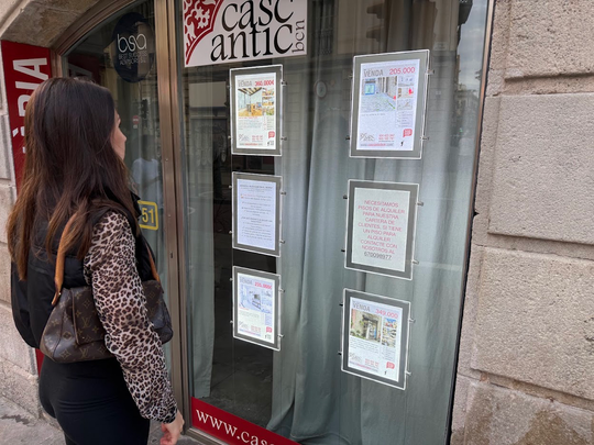 A street scene in Barcelona with a flat for rent sign visible on a building facade.