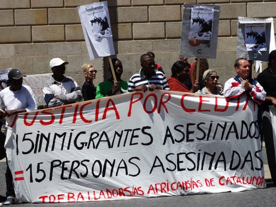 Protesters holding signs near government buildings in Barcelona during a demonstration on immigration policy.