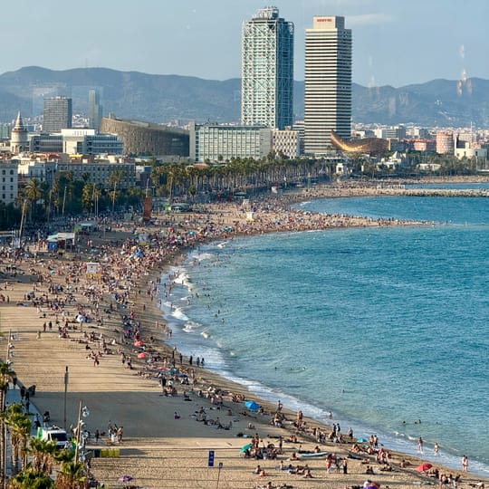 Barceloneta beach coastline with calm waters, viewed from the shore, where a recent underwater clean-up removed multiple bags of waste, primarily drink cans.