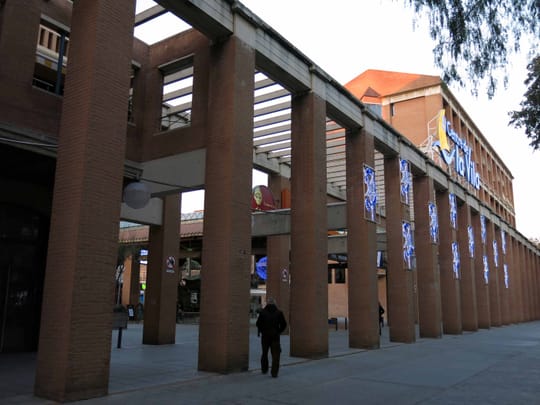 Interior of the neglected Centre de la Vila shopping centre in Barcelona's Vila Olímpica, showing empty storefronts and signs of disrepair.