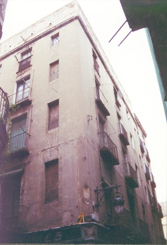 A residential building on Carrer d’Espalter in El Raval, Barcelona, showing a mix of occupied and vacant units recently acquired by the city council for public housing.
